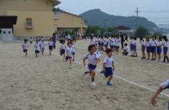 低学年に見える児童たちが一所懸命に校庭を走っている写真