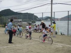 校庭に引かれた線に沿って自転車に乗っている児童たちの写真