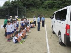 校庭に乗り入れた自動車を横二列に並んで見ている児童たちの写真