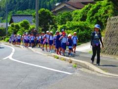 先生を先頭に歩道を並んで歩いている児童たちの写真