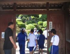 木造の門を歩いて通り抜ける児童たちの写真