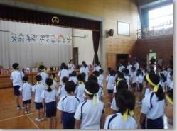 体育館で運動会に参加している児童が整列し、先生の話を聞いている写真