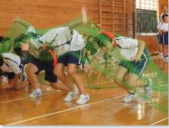 体育館で児童が網をくぐって競技をしている写真