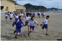 校庭で児童たちがマラソン大会で走り出して前の人を抜いている写真