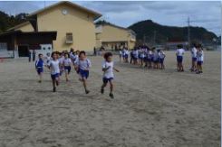 校庭で児童たちがマラソン大会で走っている写真