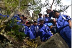 秋の遠足で岩場に児童たちが集まり笑顔で並んでいる写真