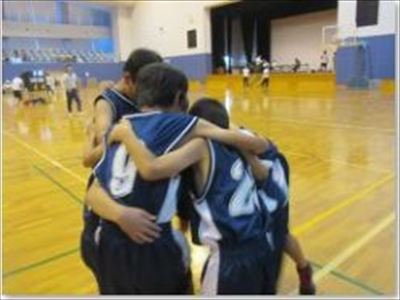 ユニフォームを着た児童たちが肩を組んで鼓舞しあってる写真