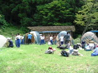 草地が広がっている場所にテントが幾つか並べられ、複数の児童たちが立っている写真