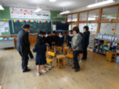 教室で円形に並べた椅子の周りに児童たちと保護者が立っている写真