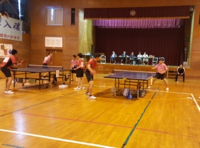体育館で複数の選手が卓球の試合をしている写真