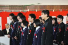 卒業式で生徒たちが胸章をつけて整列し前を向いている写真