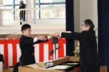 壇上で生徒が腕を伸ばし卒業証書を受け取っている写真
