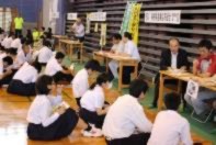 体育館で生徒が複数の面談ブースに分かれて話を聞いている写真