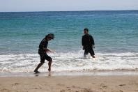 海辺で二人生徒が波打ち際に立ちはしゃいでいる写真