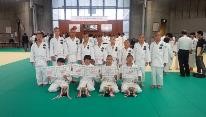 柔道大会で柔道着の子どもたちが並び賞状を持って集合している写真