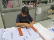 職場体験学習で生徒が机の上の書類に判子を押す作業をしている写真