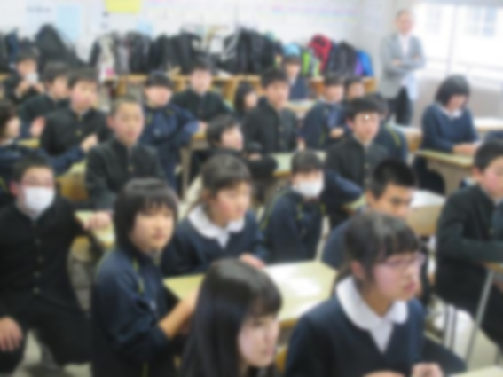 教室で多くの生徒が机に向かい前方を見て座っている写真