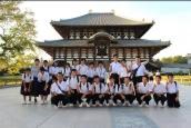 制服姿の生徒たちが寺院の前で整列して記念撮影をしている写真