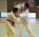 柔道着を着た2人の生徒が室内の畳の上で柔道をしている写真