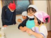 園児と生徒がエプロンと三角巾を着け、作業している写真