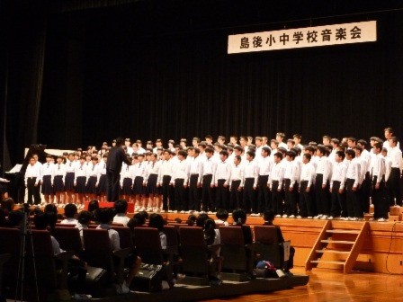 生徒がステージで横二列の長い列になって合唱している写真