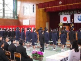 体育館で新入生がステージを向いて横二列に並んで立っている写真