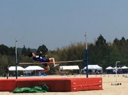 走り高跳びのバーを背面跳びで越えている選手の写真