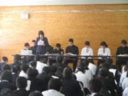 生徒会の生徒が資料を見ながらマイクで話している写真