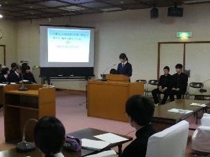 プロジェクターに映し出されたスライドの前で、生徒が発表している写真