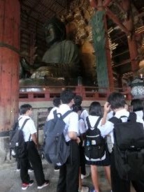 制服姿の生徒たちが大仏像の前に集まり見学している写真