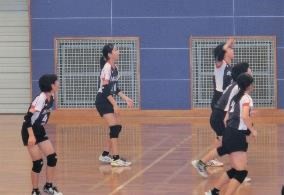 ユニフォームを着た生徒たちがバレーボールをしている写真