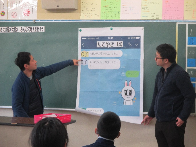 教室の黒板の前で図を使って説明している先生の写真