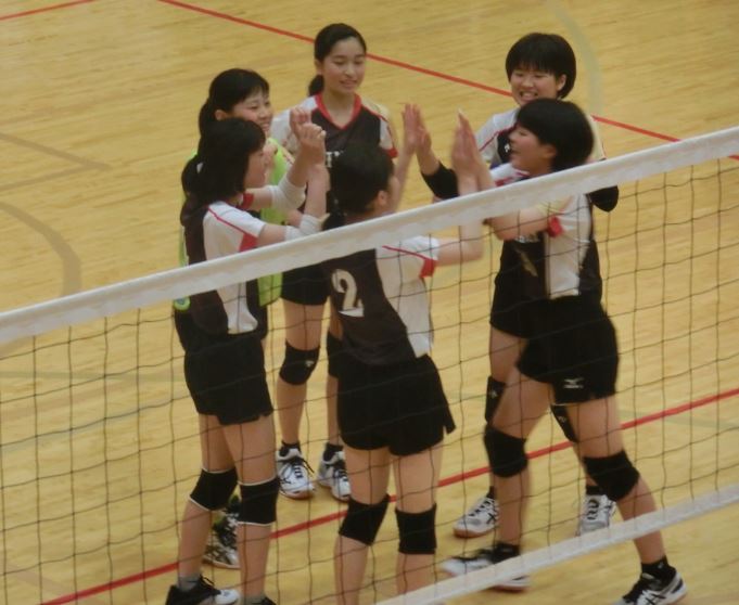 女子バレーボールの試合で選手同士でてハイタッチをしている写真