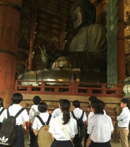 大仏の前で生徒たちや男性が立ち止まり、見学している写真