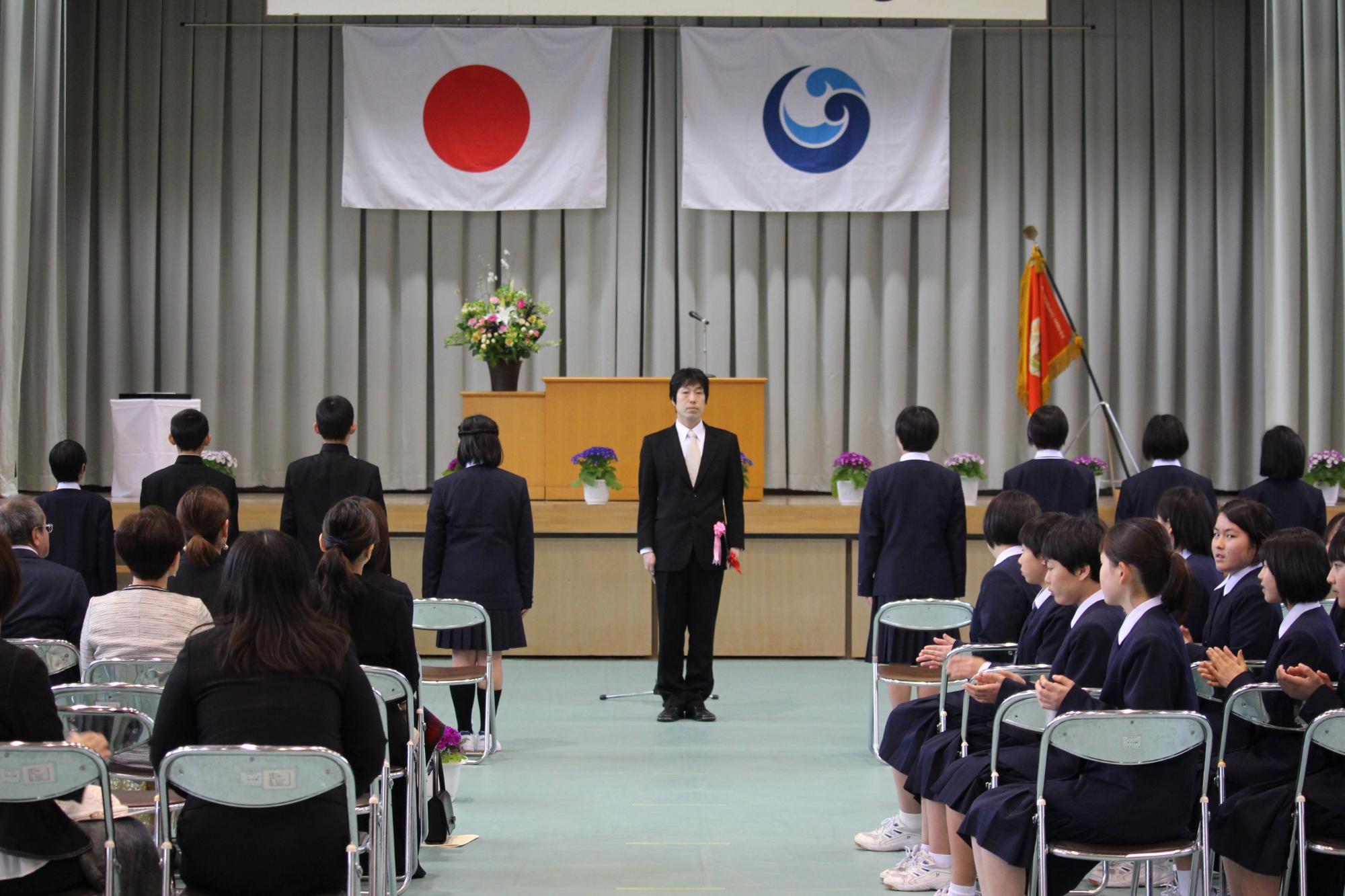 入学式で新入生がステージに向かって横に並んでいる写真