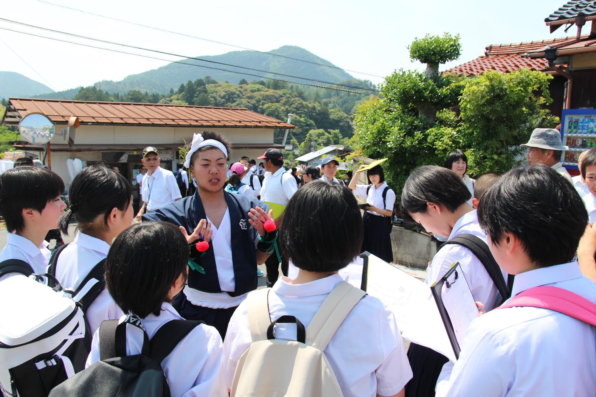 生徒たちが円になって地域の人から説明を受けている写真