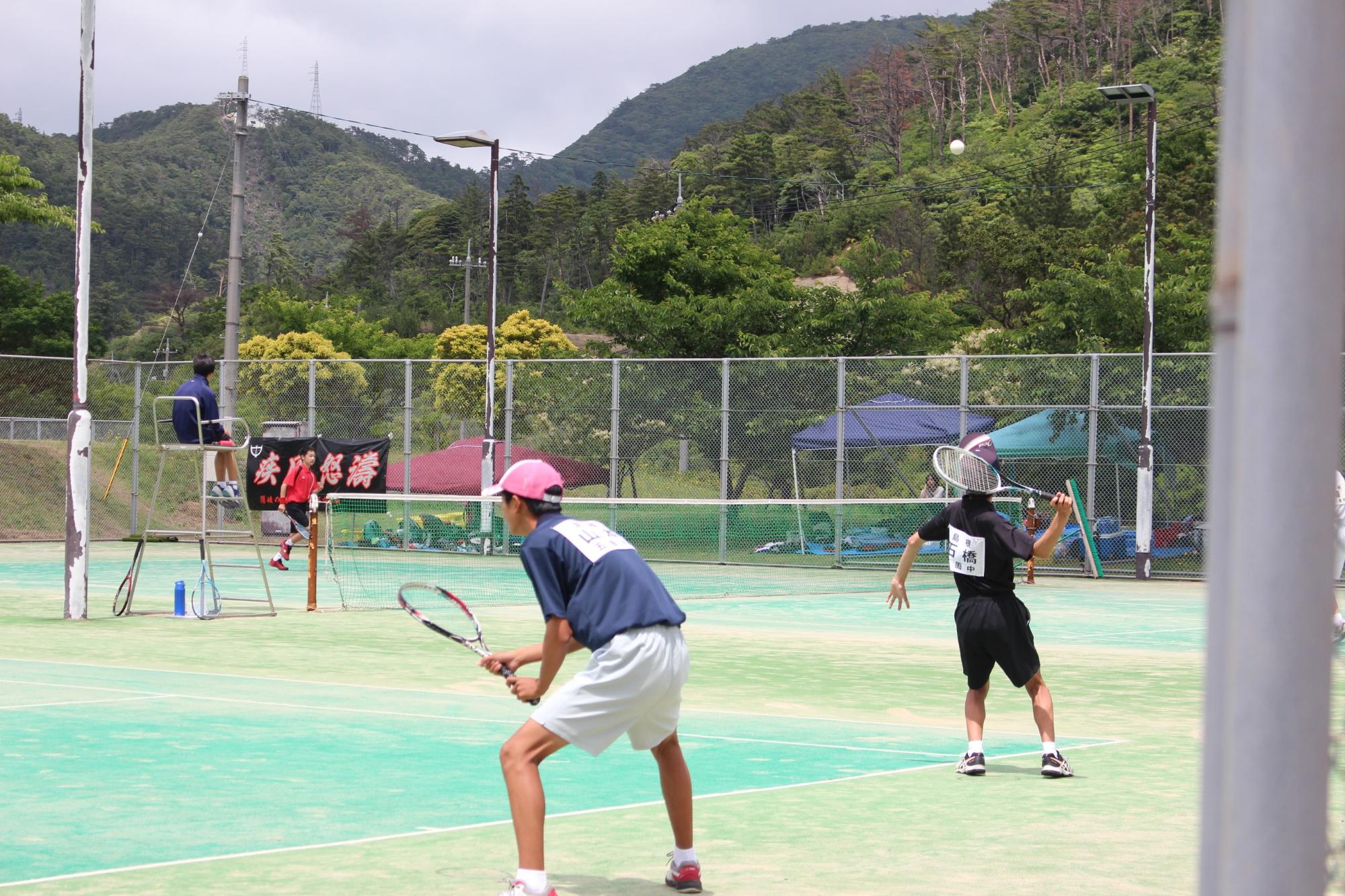 テニスの男子ダブルスの試合でサーブを打っている写真