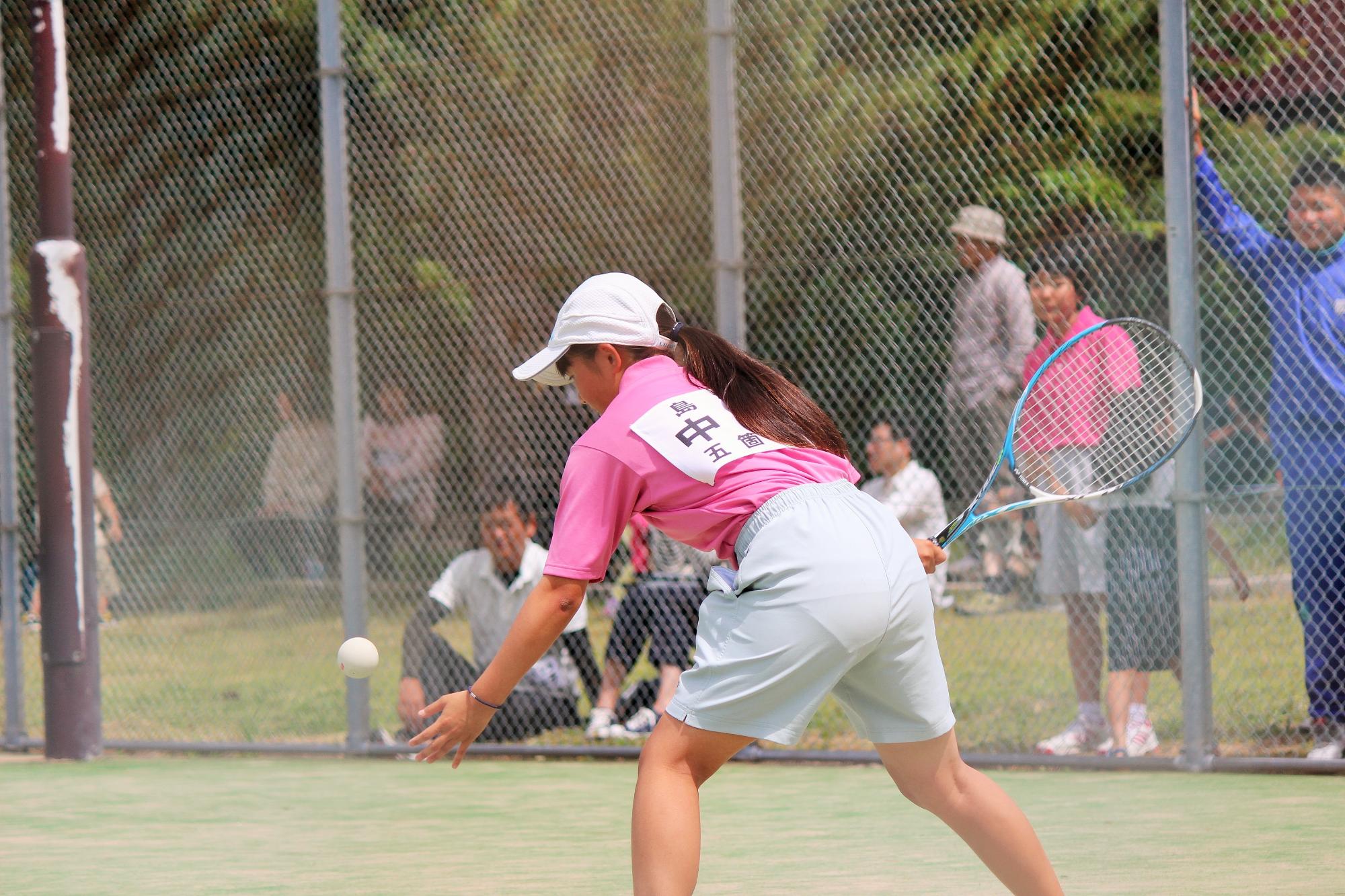 女子選手がテニスのラケットでボールを打っている写真