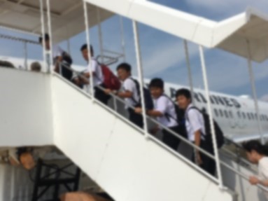 飛行機のタラップを上がっている生徒たちの写真