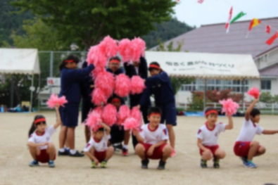 ポンポンでアルファベットのEの字を作っている生徒たちの写真