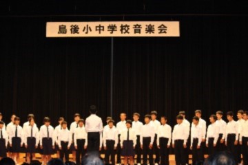 ホールのステージで合唱している生徒たちの写真