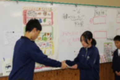 学校を代表して警察署の人に表彰される生徒の写真