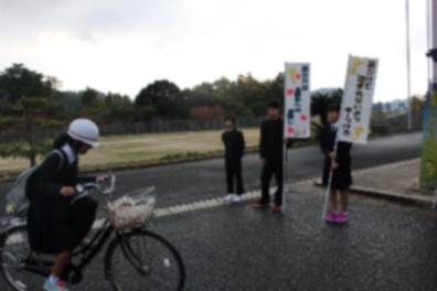 のぼり旗を持ち自転車に乗った生徒を見守る生徒たちの写真
