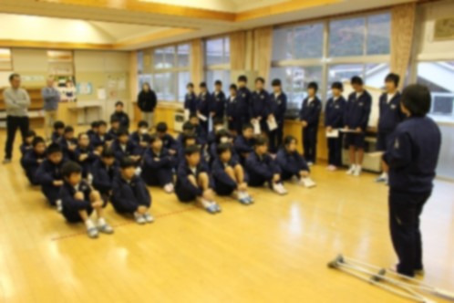 学校のホールの床に座って話を聞く生徒たちの写真