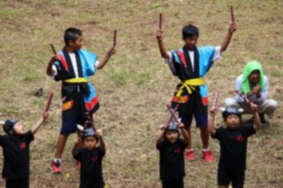 揃いの衣装で保育園児と牛突き音頭を披露している生徒の写真