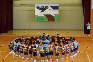 体育館のフロアで大きい円陣を組んでいる生徒たちの写真