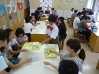 蝶ネクタイを着けた生徒が教室の模擬店で食べ物を出している写真