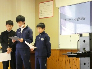 2人の生徒がモニターの前に立ち資料を手に持ちながら発表している写真