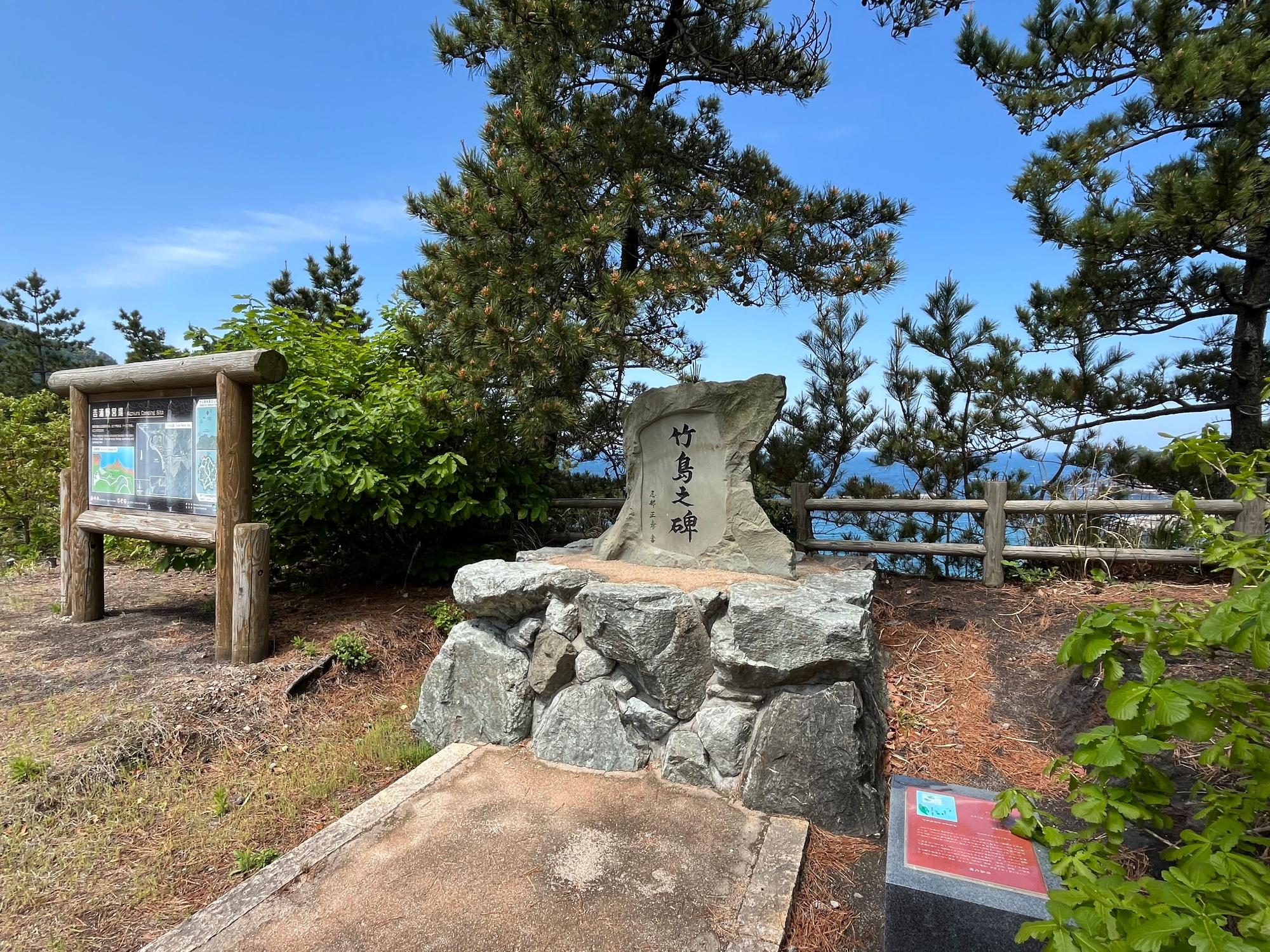 吉浦野営場にある竹島之碑の写真。隣に吉浦野営場の案内板がある。