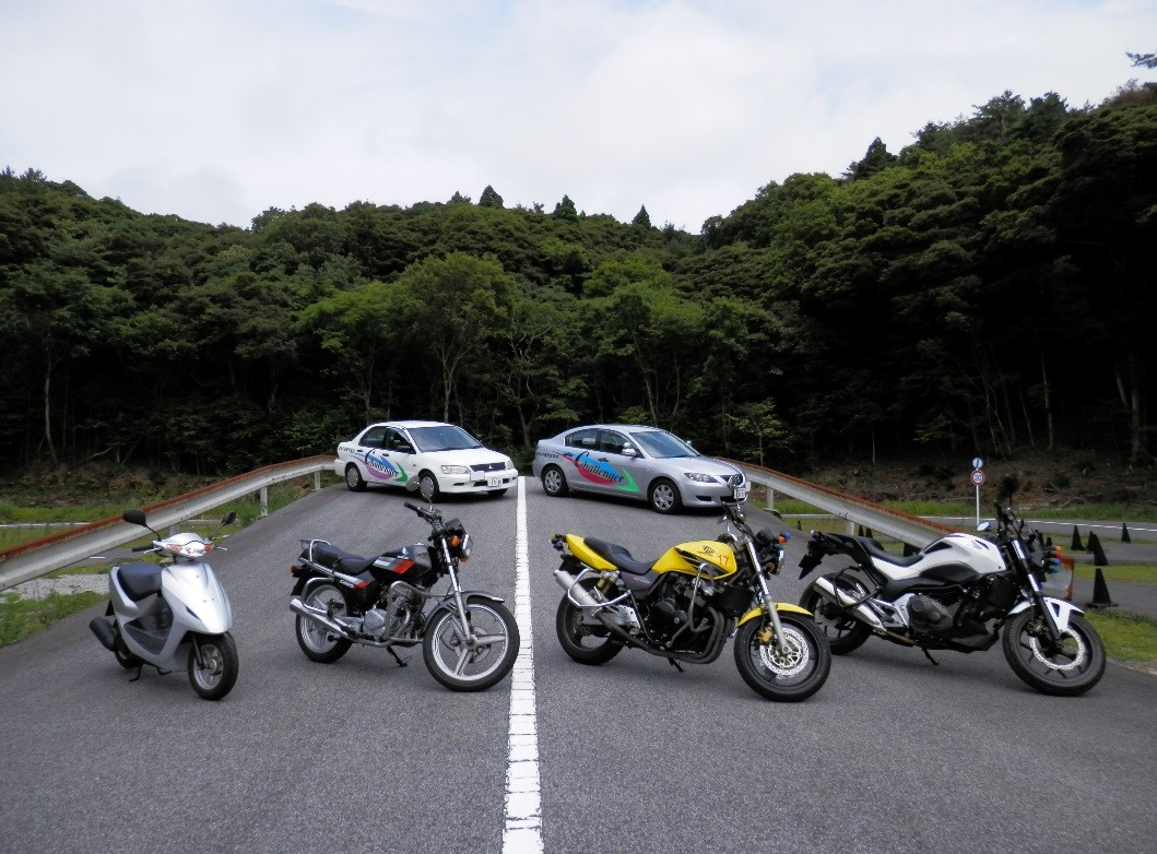 道路の奥に教習車が2台、手前に教習用バイクが4台停められている隠岐自動車練習場の写真